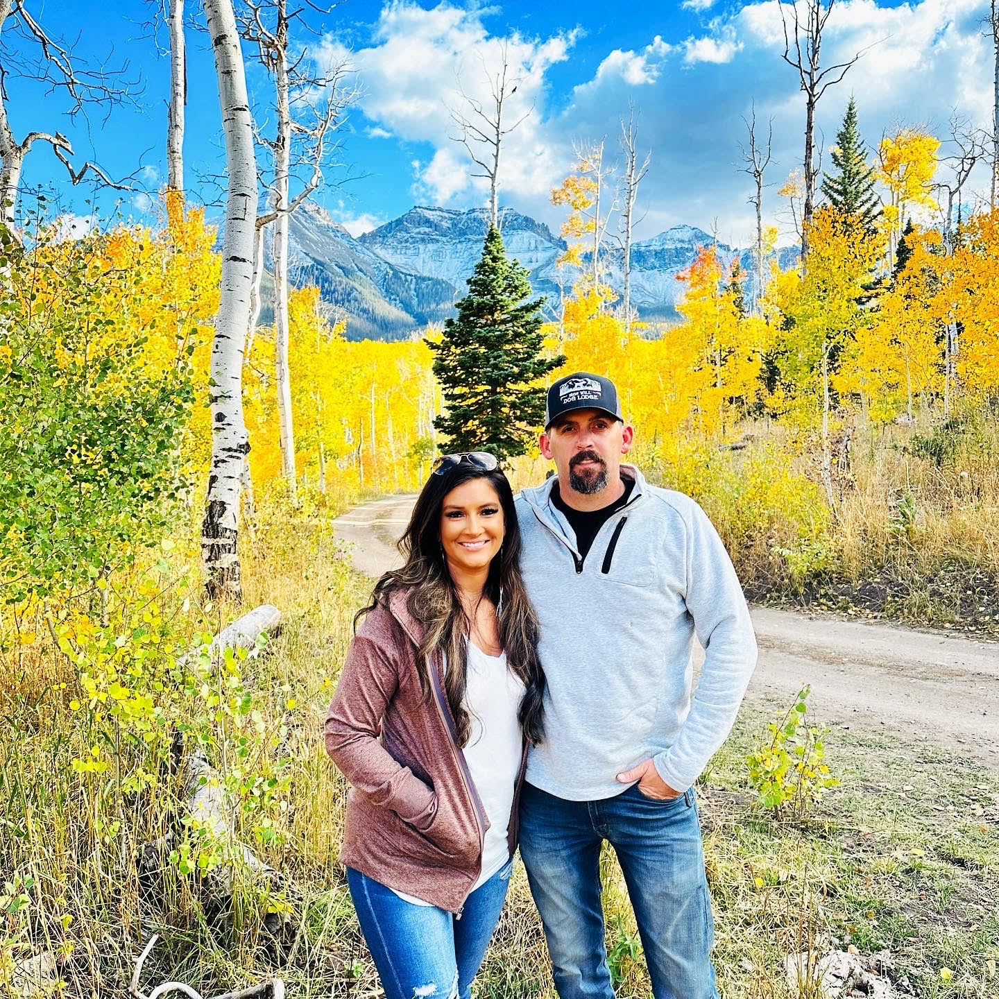 A man and woman standing in front of trees.